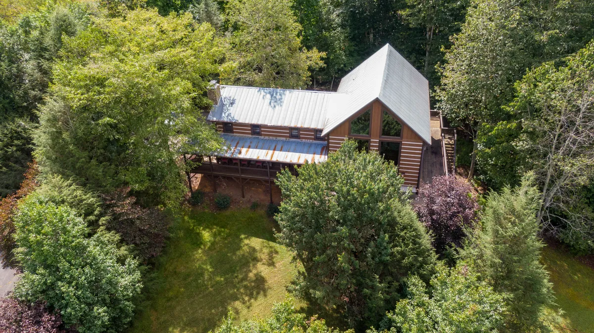 This exterior shot highlights the property's unique architectural design, surrounded by lush greenery and featuring an outdoor deck. The image evokes a sense of exploration, offering guests the chance to immerse themselves in nature, stargaze, or enjoy morning coffee outdoors.