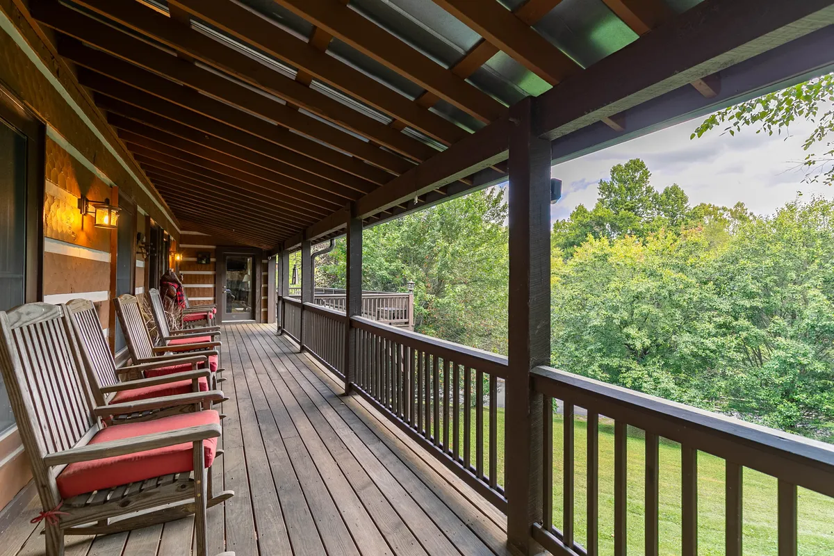 This exterior image showcases a peaceful porch with rocking chairs overlooking lush greenery. The wooden railing and natural setting evoke a sense of relaxation and provide a direct visual connection to the great outdoors, inviting guests to unwind while soaking in the surrounding landscape.