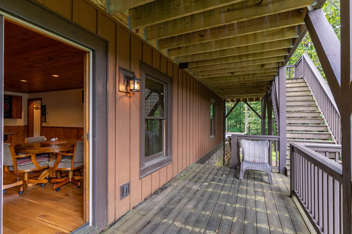 An inviting wooden deck equipped with outdoor seating, direct access to the house, and views of surrounding nature. The open door hints at seamless movement between indoor comforts and outdoor enjoyment, ideal for group activities and making the most of Boone's scenic location.