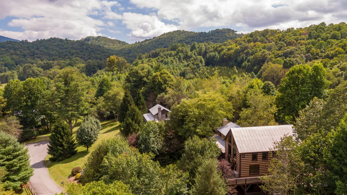 This shot captures rustic wooden cabins nestled amid lush greenery and rolling hills, with ample space for hiking and outdoor play. The landscape evokes the scenic beauty of the Blue Ridge Mountains and the opportunities for hiking and nature walks nearby.