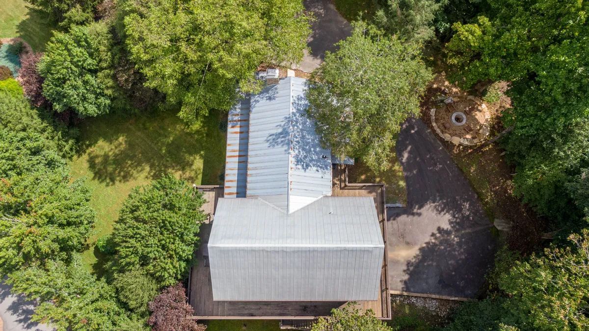 This exterior shot features the house surrounded by lush greenery, a welcoming patio area, and a cozy fire pit. The setup is ideal for group gatherings, evening fireside chats under the stars, and outdoor entertainment—perfectly aligning with the section's focus on bonding and in-home fun after a day of adventure.